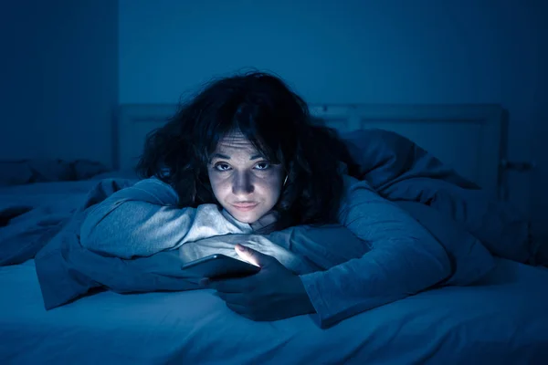 チャットや夜遅くの眠そうな 疲れている彼女のスマート フォンを使用してインターネット上でサーフィン中毒若い女性 劇的な暗い光 インターネット 携帯依存症 不眠症の概念 — ストック写真