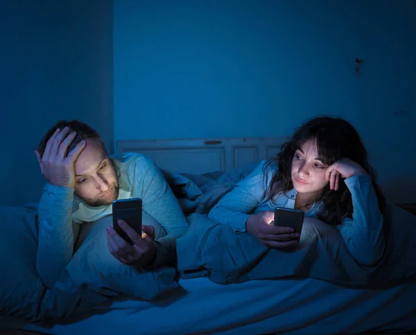 Retrato Estilo Vida Jovem Casal Entediado Cama Noite Telefones Inteligentes — Fotografia de Stock