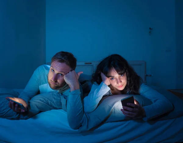 Retrato Estilo Vida Jovem Casal Entediado Cama Noite Telefones Inteligentes — Fotografia de Stock