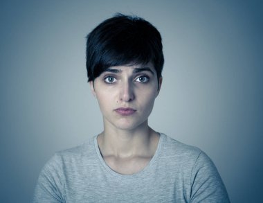 Mutsuz yüzü sefil ve depresif görünümlü güzel üzgün genç kadının Portresi. İnsan yüz ifadeleri, olumsuz duygular ve duygusal acı kavramı. mavi karamsar ışık ile izole arka plan.