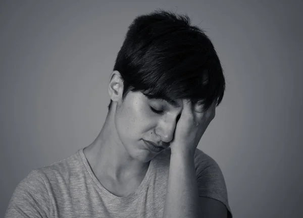 Black and white portrait of beautiful young sad caucasian woman suffering from depression looking miserable and melancholy. Human facial expressions and emotions concept. Grey background