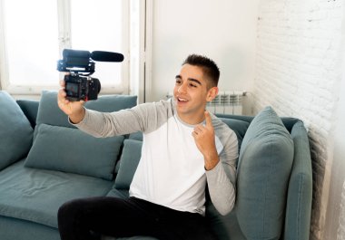 Kendi kendine portre fotoğraf çekim veya evde streaming video kaydı kamera tutarak rahat kıyafetler tarzı genç sevimli adam. Sosyal medya etkileyen, Internet takipçileri ve blogger kavramı.
