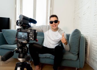 Video kamera tripod ile blogunuzda evde çevrimiçi takipçileri için filme onun yirmili üzerinde mutlu trendy beyaz erkek. Sosyal medya, etkileyen, yeni teknoloji, iletişim ve Internet kavramı.