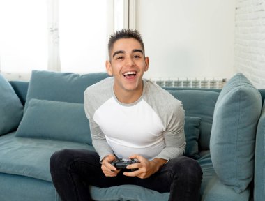 Video having oyunculuk ile konsol oyun İstasyonu ve video erkek oyun bağımlılığı ucube yoğun mutlu yüzüne kablosuz uzaktan joystick kullanarak oyunu kazanma oyunları oynamak genç öğrenci adam portresi.