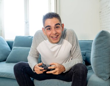 Video having oyunculuk ile konsol oyun İstasyonu ve video erkek oyun bağımlılığı ucube yoğun mutlu yüzüne kablosuz uzaktan joystick kullanarak oyunu kazanma oyunları oynamak genç öğrenci adam portresi.
