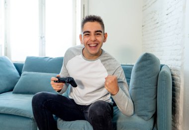 Video having oyunculuk ile konsol oyun İstasyonu ve video erkek oyun bağımlılığı ucube yoğun mutlu yüzüne kablosuz uzaktan joystick kullanarak oyunu kazanma oyunları oynamak genç öğrenci adam portresi.