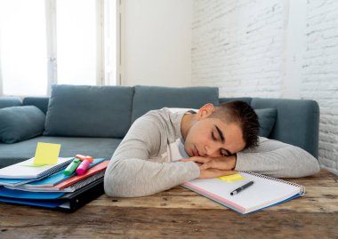 Çalışma ve eğitim yapacak işleri ve yorgun üniversite ya da lise erkek öğrenci sıkılmış ve uykuya düşmemeye çalışırken boğulmuş. Son sınıf sınav, ödev için bir öğrenme eğitim zorluklar kavramı.