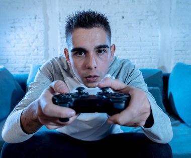 Ucube yoğun bağımlısı yüz erkek oyun bağımlılığı konsol oyun istasyonu ve video having oyunculuk ile kablosuz uzaktan joystick kullanarak gece video oyunları oynarken genç öğrenci adam portresi.