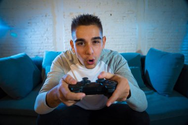 Ucube yoğun bağımlısı yüz erkek oyun bağımlılığı konsol oyun istasyonu ve video having oyunculuk ile kablosuz uzaktan joystick kullanarak gece video oyunları oynarken genç öğrenci adam portresi.