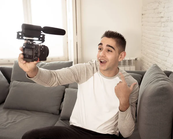 Young cute man in casual clothes style holding camera shooting self portrait photo or recording video in streaming at home. In Social Media Influencer, internet followers and blogger concept.