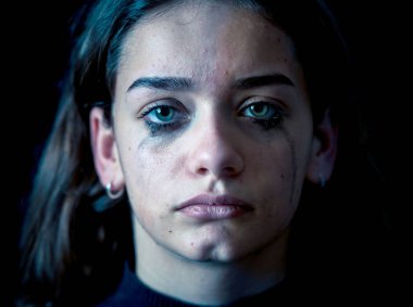 Ağlayan bir okulda, depresif, yalnız, yorgun, stresli genç çocuk kız closeup. Siyah arka plan üzerine izole. İnsan duyguları, çocukluk depresyon, duygusal acı. Zorbalık ve çocuk istismarı kavramı.