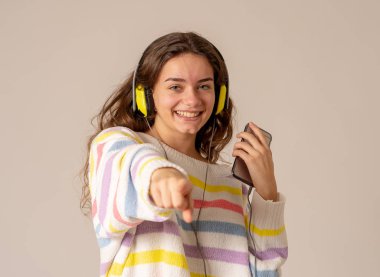 Güzel ve mutlu genç kadın müzik şarkı ve tarafsız arka plan üzerinde dans Kulaklığımda mutlu portre. Olumlu duygular, gençlik, insanlar, eğlence ve teknoloji kavramı.