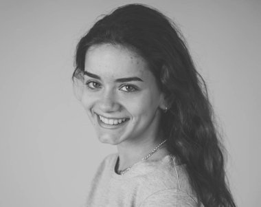 Siyah beyaz portre sevimli gülümseme ve şık bir görünüm ve pozlar güzel genç genç kadının kapatın. Mutluluk, güzellik ve moda ve insanlar kadın kavramı. Gri arka plan üzerinde izole.