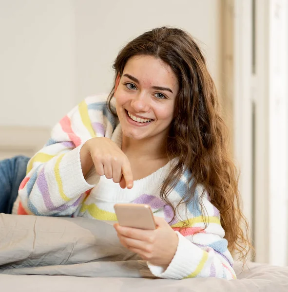 スマート フォンの信者をチェックし インターネット ソーシャル メディア 新しい技術コンセプトの家でモバイル アプリケーションを使用してオンライン チャットで幸せな魅力的な若い 代女性 — ストック写真