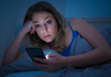 Sohbet ve telefon bağımlılığı ve teknoloji aşırı kavramı gece geç saatlerde akıllı telefonunu uykulu, donuk ve yorgun kullanarak Internet sörf bağımlısı genç güzel kadın yatakta,.