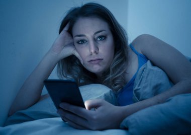 Sohbet ve telefon bağımlılığı ve teknoloji aşırı kavramı gece geç saatlerde akıllı telefonunu uykulu, donuk ve yorgun kullanarak Internet sörf bağımlısı genç güzel kadın yatakta,.