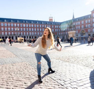 Güzel genç Kafkas kadın mutlu ve heyecanlı Plaza Mayor Madrid bir selfie veya mobil akıllı telefon ve eğleniyor sopa video alma. Seyahat ve sörf dünyanın turizm, öğrenci yaşam tarzı.
