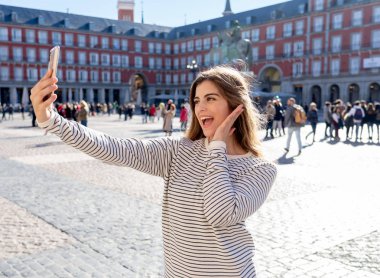 Güzel genç beyaz öğrenci turist kadın bir selfie veya onu turizm ve seyahat etmek çevrede Dünya blog web Plaza Mayor Madrid İspanya için video alma. Sosyal medya ve Avrupa'da tatil.