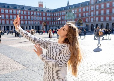 Güzel genç beyaz öğrenci turist kadın bir selfie veya onu turizm ve seyahat etmek çevrede Dünya blog web Plaza Mayor Madrid İspanya için video alma. Sosyal medya ve Avrupa'da tatil.