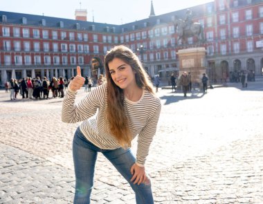 Güzel genç turist kadın mutlu ve heyecanlı Plaza Mayor Madrid İspanya bakarak eğleniyor ve güneşli bir günde işareti Yaşasın yapıyor neşeli. Avrupa ve öğrenci boşluk yıl çevresinde turizm, seyahat.