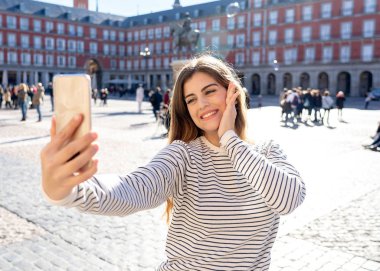 Güzel genç beyaz öğrenci turist kadın bir selfie veya onu turizm ve seyahat etmek çevrede Dünya blog web Plaza Mayor Madrid İspanya için video alma. Sosyal medya ve Avrupa'da tatil.