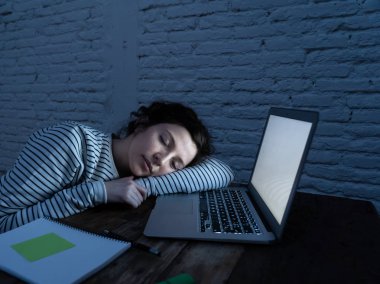 Aşırı çalışmış ve yorgun kadın öğrenci masanın üzerinde uyurken gece geç saatlere kadar onun laptop üzerinde çalışırken. Yorgunmuş ve uykusu masasında dinleniyor. Sınav veya aşırı iş konsepti için eğitim.