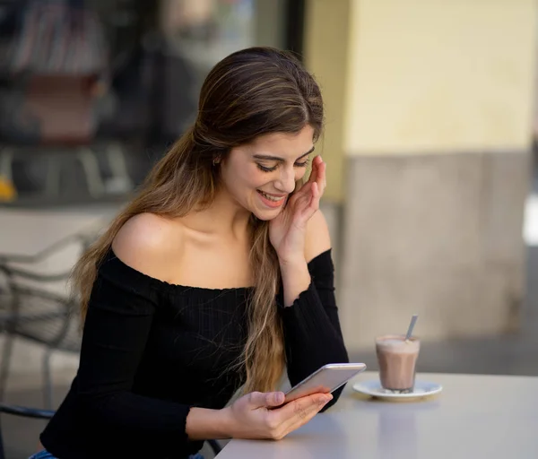 漂亮的年轻时尚的女人喜欢喝咖啡 检查消息和喜欢在智能手机在咖啡店的露台上 在生活方式 博客作者和追随者和技术移动使用的概念 — 图库照片
