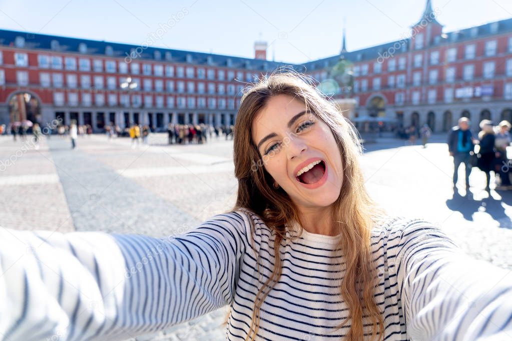 Beautiful student tourist woman happy and excited taking close up selfie in Plaza Mayor Madrid Looking cheerful and joyful having fun. In tourism, travel around europe and posting online adventures.