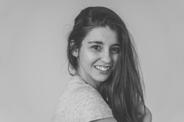 Mutlu yüz, güzel gülümseme ve uzun saçlı genç güzel kadın siyah ve beyaz portre. Rahat kıyafetler giyip omzunun arkasına bakmak. Güzellik, modelleme ve poz verme konseptinde.