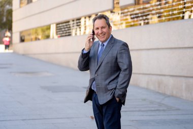 Orta yaşlı işadamı kentsel City akıllı cep telefonunda mutlu insanlar dışında sokak konuşuyor. Sosyal ağ, özgürlük, modern teknoloji ve girişimci yaratıcı iş kavramı.