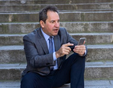 Akıllı telefon e-posta ve sosyal medya şehir merdivenlerde kontrol üzerinde mutlu orta yaşlı işadamı. İnsanlar, yeni teknoloji, online bağlantı ve girişimci yaratıcı iş mobil iletişim kavramı.