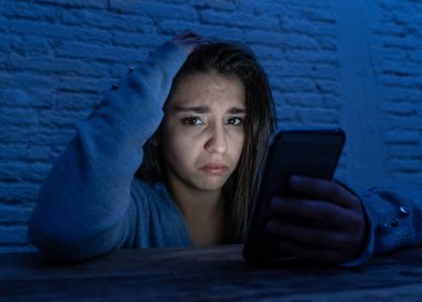 Üzücü korkmuş genç kadın çevrimiçi taciz ve siber zorbalık kurbanı dramatik portresi. akıllı cep telefonu bakarak vurguladı ve korku online Stalker tarafından istismar olmak. İnternet tehlikeleri.