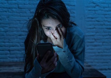 Siber zorbalık ve taciz acı akıllı cep telefonu üzücü korkmuş genç kadının dramatik portresi. Yalnız, depresif ve korku online Stalker tarafından istismar olma hissi. İnternet tehlikeleri.