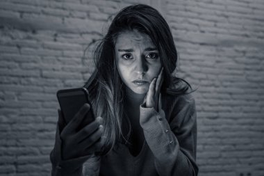 Üzgün korkmuş genç kadının dramatik siyah beyaz portre stresli ve siber zorbalık ve taciz acı telefonu ile endişeli. tarafından çevrimiçi olarak suistimal ediliyor. Internet sorun kavramında.