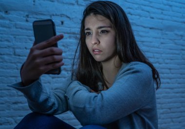 Gece katta üzgün korkmuş genç kadın portre vurguladı ve akıllı cep telefonu tehdit siber zorbalık taciz muzdarip. Stalker tarafından istismar online olmak umutsuz ve depresif.