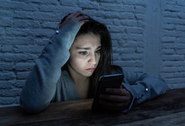 Üzücü korkmuş genç kadın çevrimiçi taciz ve siber zorbalık kurbanı dramatik portresi. akıllı cep telefonu bakarak vurguladı ve korku online Stalker tarafından istismar olmak. İnternet tehlikeleri.