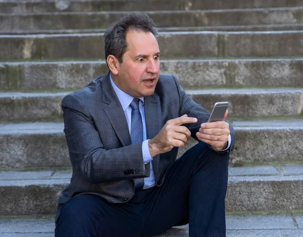 Akıllı telefon e-posta ve sosyal medya şehir merdivenlerde kontrol üzerinde mutlu orta yaşlı işadamı. İnsanlar, yeni teknoloji, online bağlantı ve girişimci yaratıcı iş mobil iletişim kavramı.