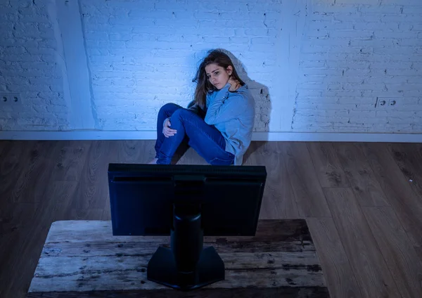 悲伤的年轻女子独自在地上盯着电脑承受欺凌和骚扰的戏剧性画像 在网络问题概念中被跟踪者虐待感到绝望 — 图库照片