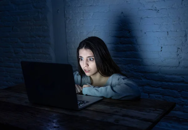 Dramatic portrait of sad and scared young woman with laptop suffering cyber bullying and harassment. Being online abused by stalker feeling desperate and humiliated in Internet problem concept.
