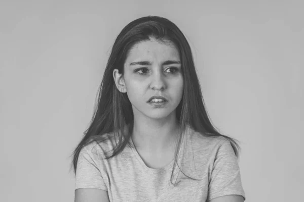 Black and white close up of a young sad woman, serious and concerned, looking worried and thoughtful. Feeling sorrow and depression. With copy space. In facial expressions and human emotions concept.