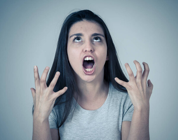 Portrait of young attractive frustrated latin woman with angry and stressed face. Looking mad and crazy shouting and making furious gestures. Facial expressions and emotions and mental health.