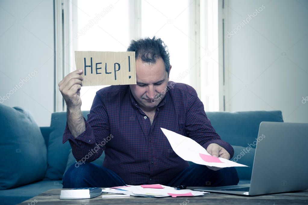 Worried and desperate mature man asking for help in paying off debts and loan calculating bills tax expenses and accounting home finances on couch in Domestic bills and Financial problems concept.