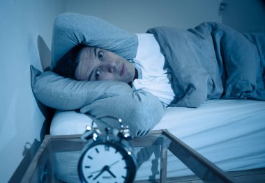 Uykusuz ve çaresiz genç beyaz adam Uykusuz geceleri uyku mümkün değil, hayal kırıklığına ve stres ve uyku bozukluğu kavramı uykusuzluk muzdarip saat bakıyor endişeli.