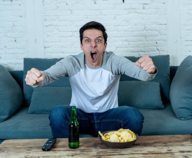 Heyecan verici futbol hayranı yaşam tarzı portre televizyonda futbol veya futbol oyunu izlerken eğlenceli. Zevk ve gol ve zafer bira içme ve cips yeme kutluyor. Spor hayranları ve gol.