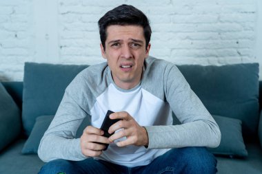 Yaşam tarzı portre genç adam korkuyor ve korku yapma şok, anksiyete jestleri televizyon tutarak uzaktan kumanda izlerken duygu. TV ve internet ve kitle iletişim sisteminde korku ve şiddet.