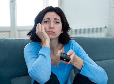 Genç üzgün kadın kanepede kontrol uzaktan zapping kullanarak kötü Tv şovları ve programlama sıkılmış . İlgisiz, ilgisiz ve uykusuz görünüyor. İnsanlar, çok fazla kötü televizyon ve Sedanter yaşam tarzı.