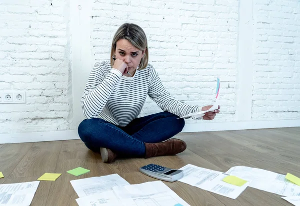 Portrait of worried young woman feeling stressed and desperate on the ground with calculator accounting expenses not able to pay mortgage. In paying debts and domestic bills and financial problems.