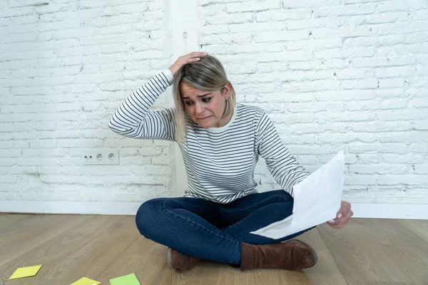 Portrait of worried young woman feeling stressed and desperate on the ground with calculator accounting expenses not able to pay mortgage. In paying debts and domestic bills and financial problems.