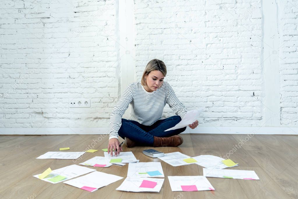 Portrait of worried young woman feeling stressed and desperate on the ground with calculator accounting expenses not able to pay mortgage. In paying debts and domestic bills and financial problems.