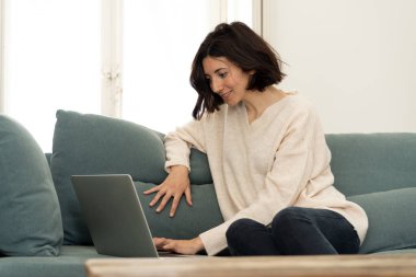 Bilgisayar dizüstü bilgisayar kullanarak çekici rahat kadın Lifestyle portre, online film izlerken zevk, sosyal medya tarama ve çalışma veya evde eğitim. İnternet teknolojisi ve ağ konseptinde.